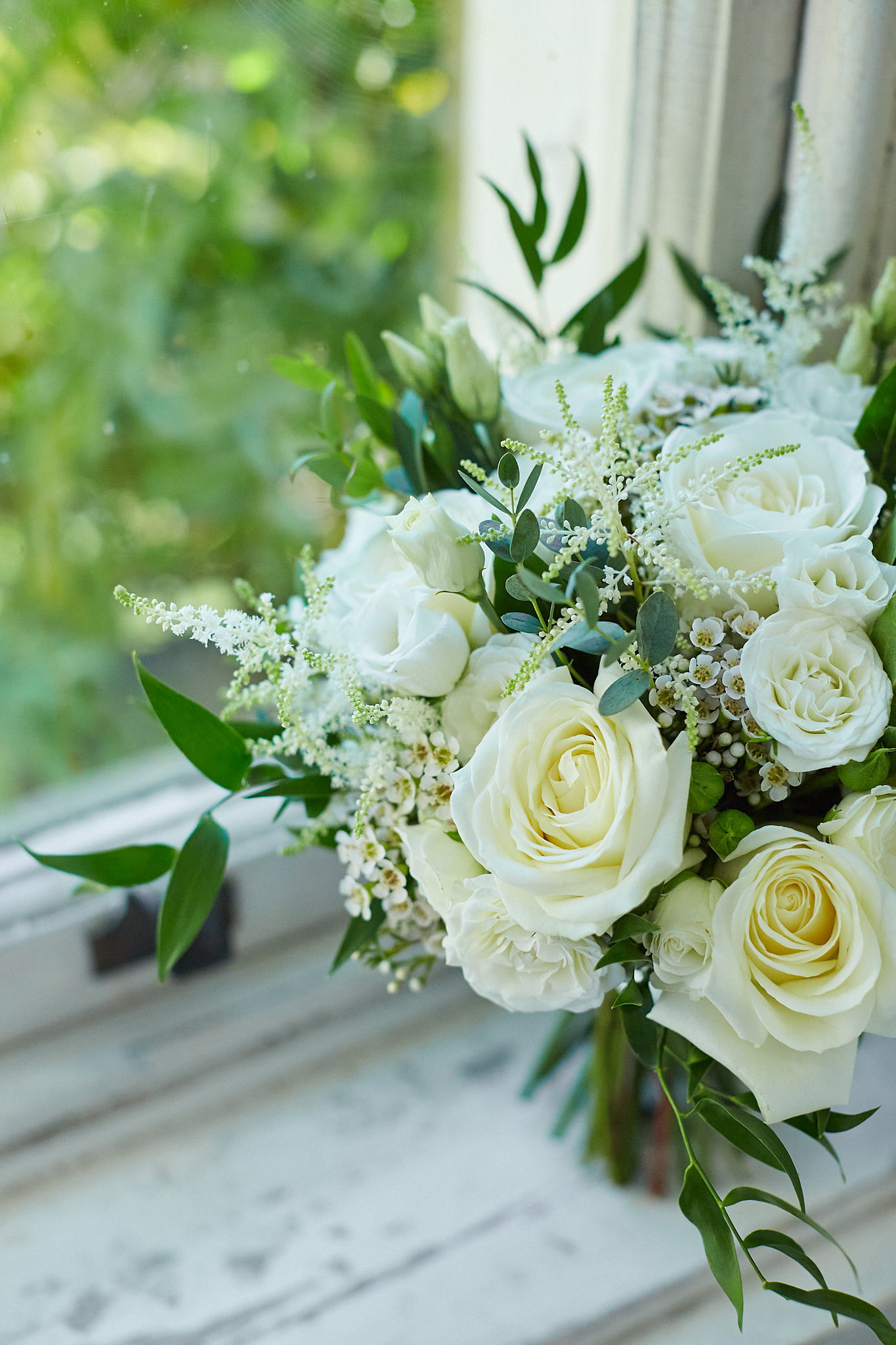Green and white bridal bouquet sat on window ledge